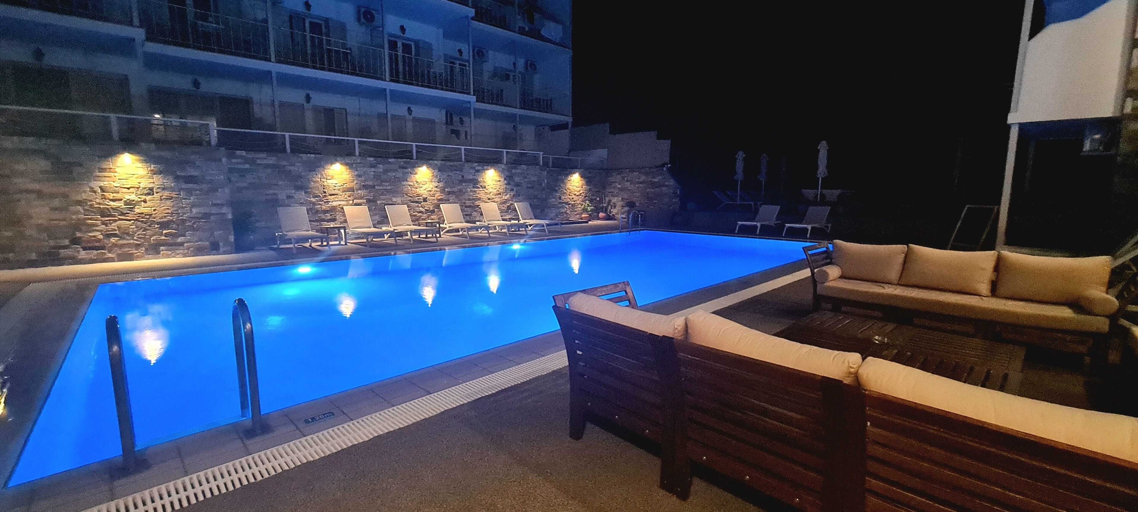 A swimming pool with lounge chairs and a stone wall.