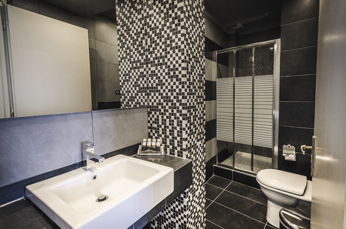 A modern bathroom with a checkered tile wall, a white sink, and a toilet.
