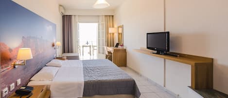A hotel room with a large bed, a desk with a computer, a television, and a painting on the wall.