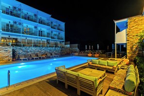 A pool area with lounge chairs and a seating area, surrounded by a building with multiple balconies.