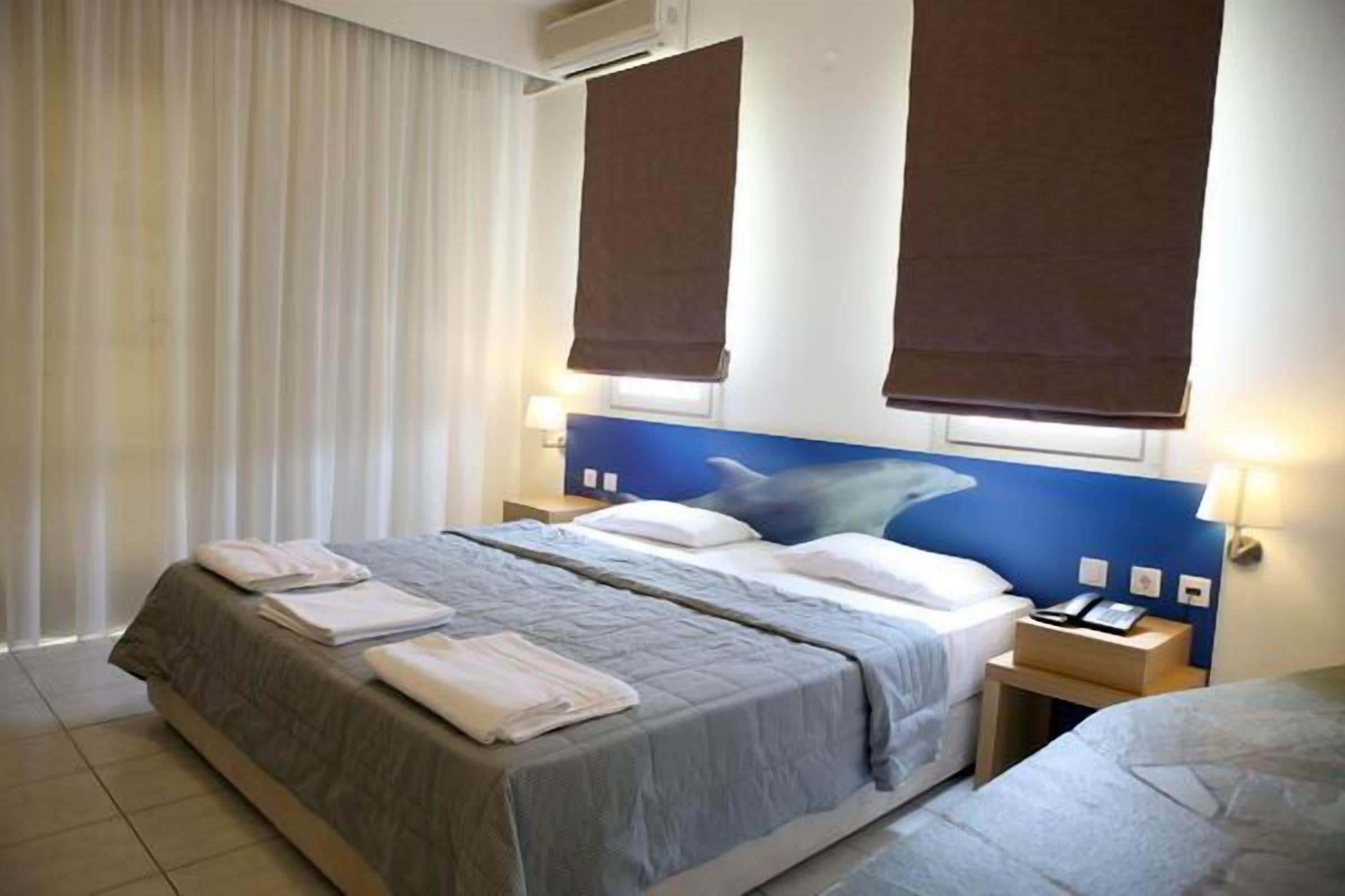 A hotel room with a large bed, two bedside tables, a nightstand, and a window with curtains.