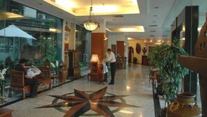 A hotel lobby with a large star-shaped floor design, wooden furniture, and a person standing near a table. - Paragon Gallery Hotel Jakarta (Jakarta)