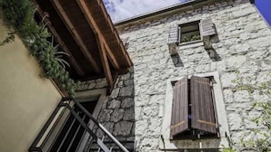 Un edificio de piedra con contraventanas de madera y un balcón.