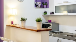 Una cocina con encimera de madera, microondas, fregadero y un reloj en la pared.