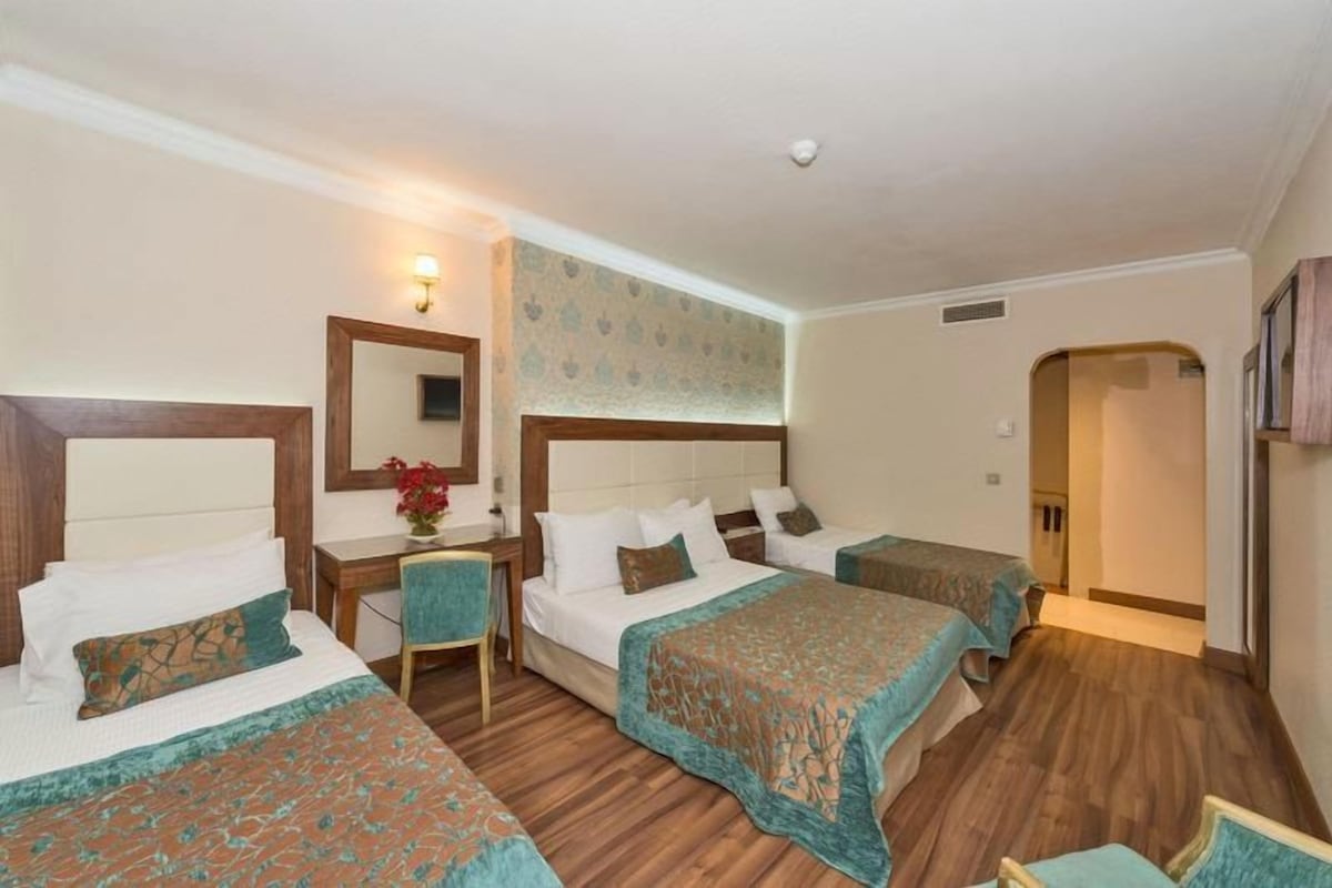 Une chambre d’hôtel avec deux lits, un bureau et une chaise.