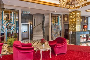 A luxurious lobby with a grand staircase, red upholstered chairs, a checkered floor, and a chandelier. - Green Anka Hotel (Istanbul)