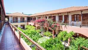 A courtyard with a tiled walkway, wooden railings, and a building with multiple windows and balconies.
