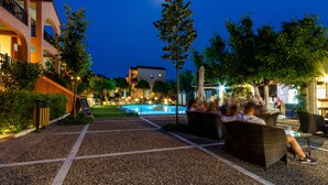 An outdoor pool area with seating and a view of a building in the background. - Rigas Hotel Skopelos by GHH (Skopelos)