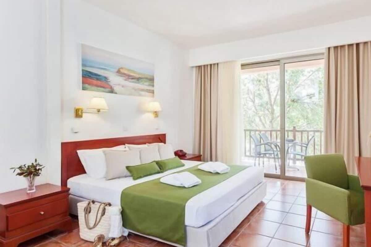 Relax in comfort with a neatly made bed, a TV, and a view of the outdoors.
