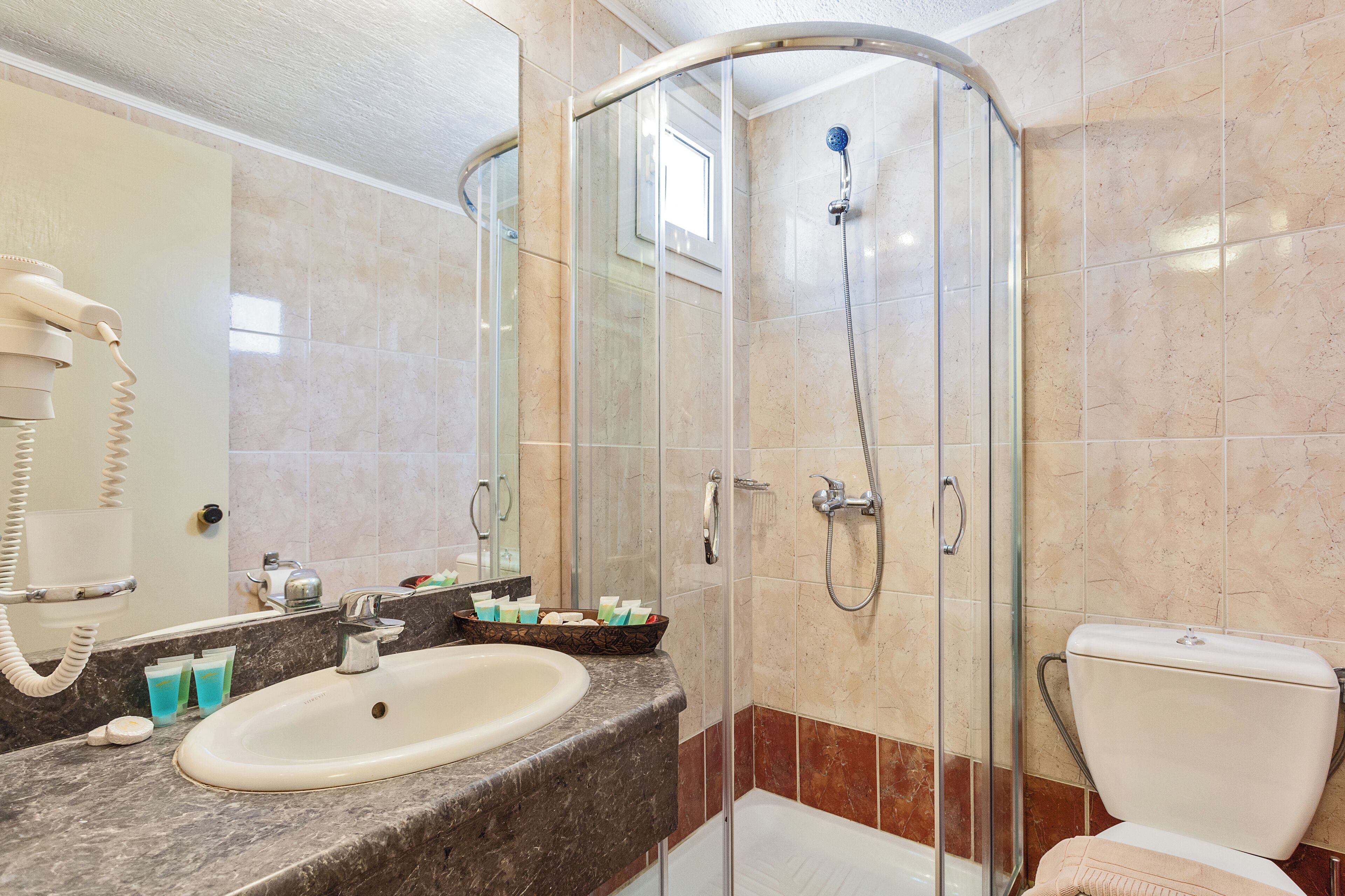Une salle de bain avec une douche à parois de verre, un lavabo équipé de produits de toilette et des toilettes.