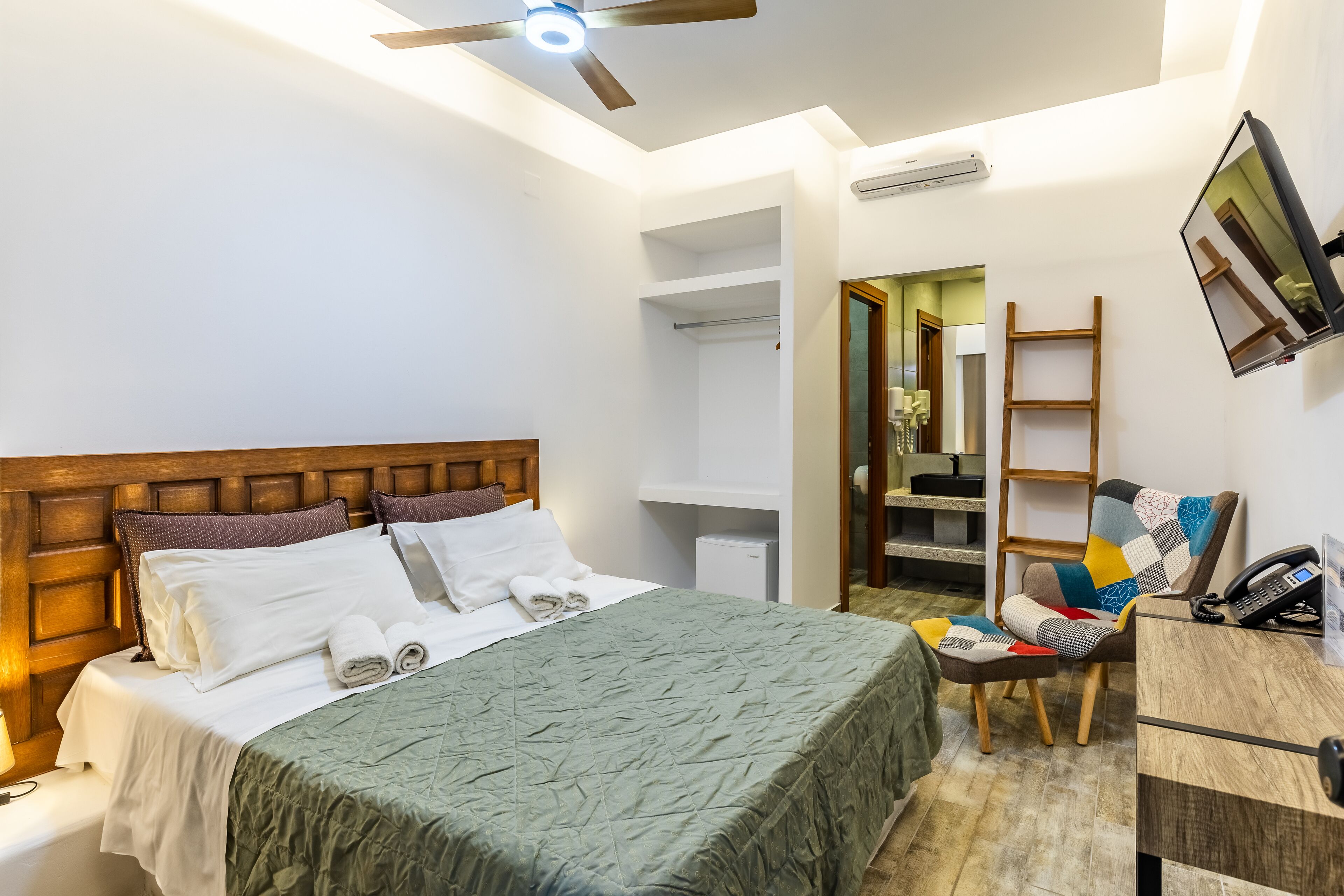 Habitación de hotel ordenada con cama, escritorio, silla y armario.
