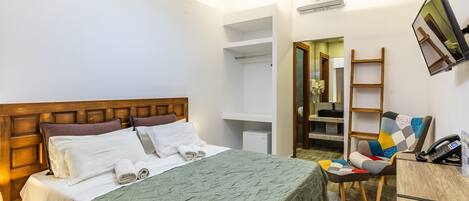 Habitación de hotel ordenada con cama, escritorio, silla y armario.