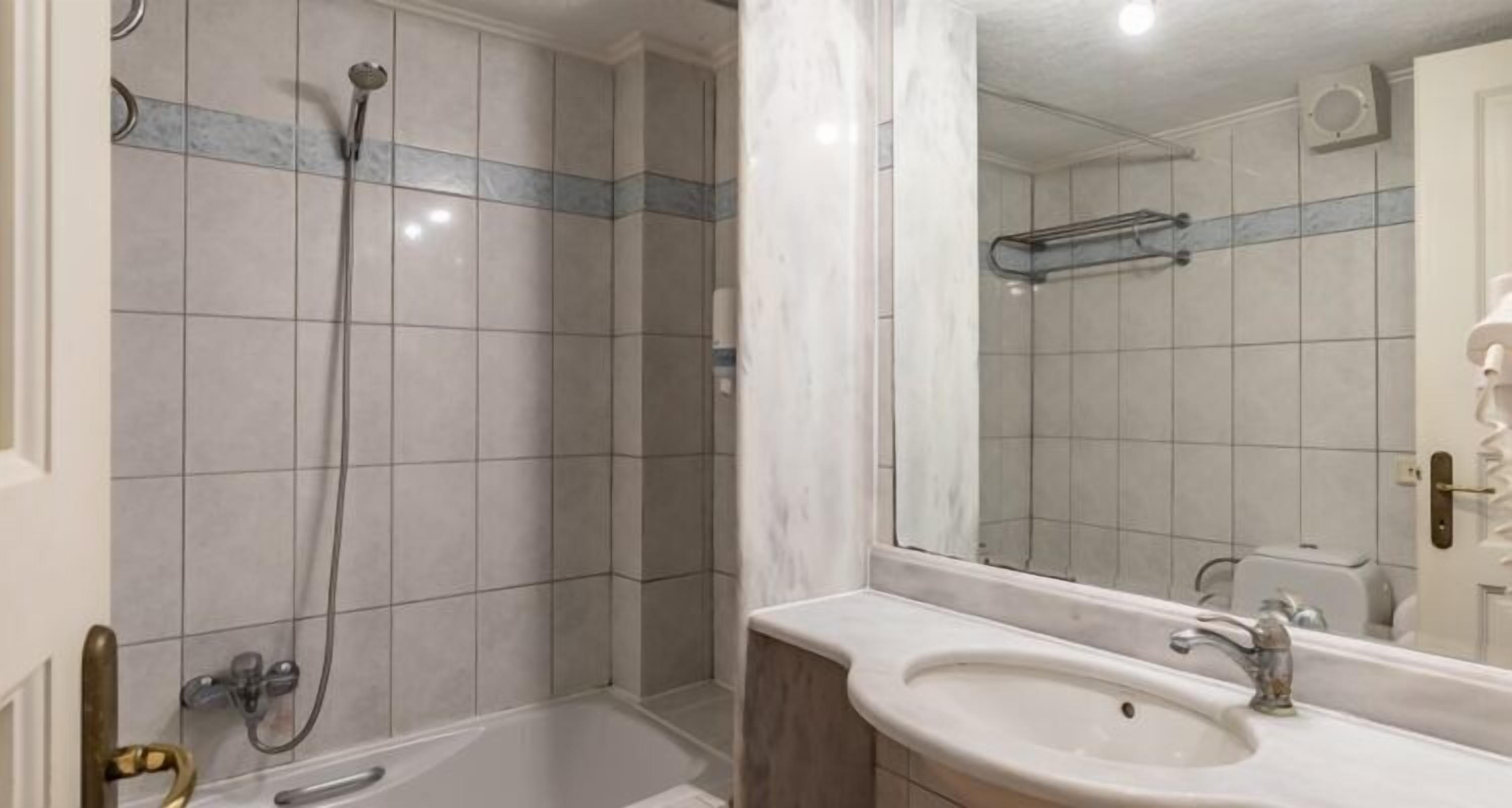 A bathroom with a shower, a sink, and a mirror.