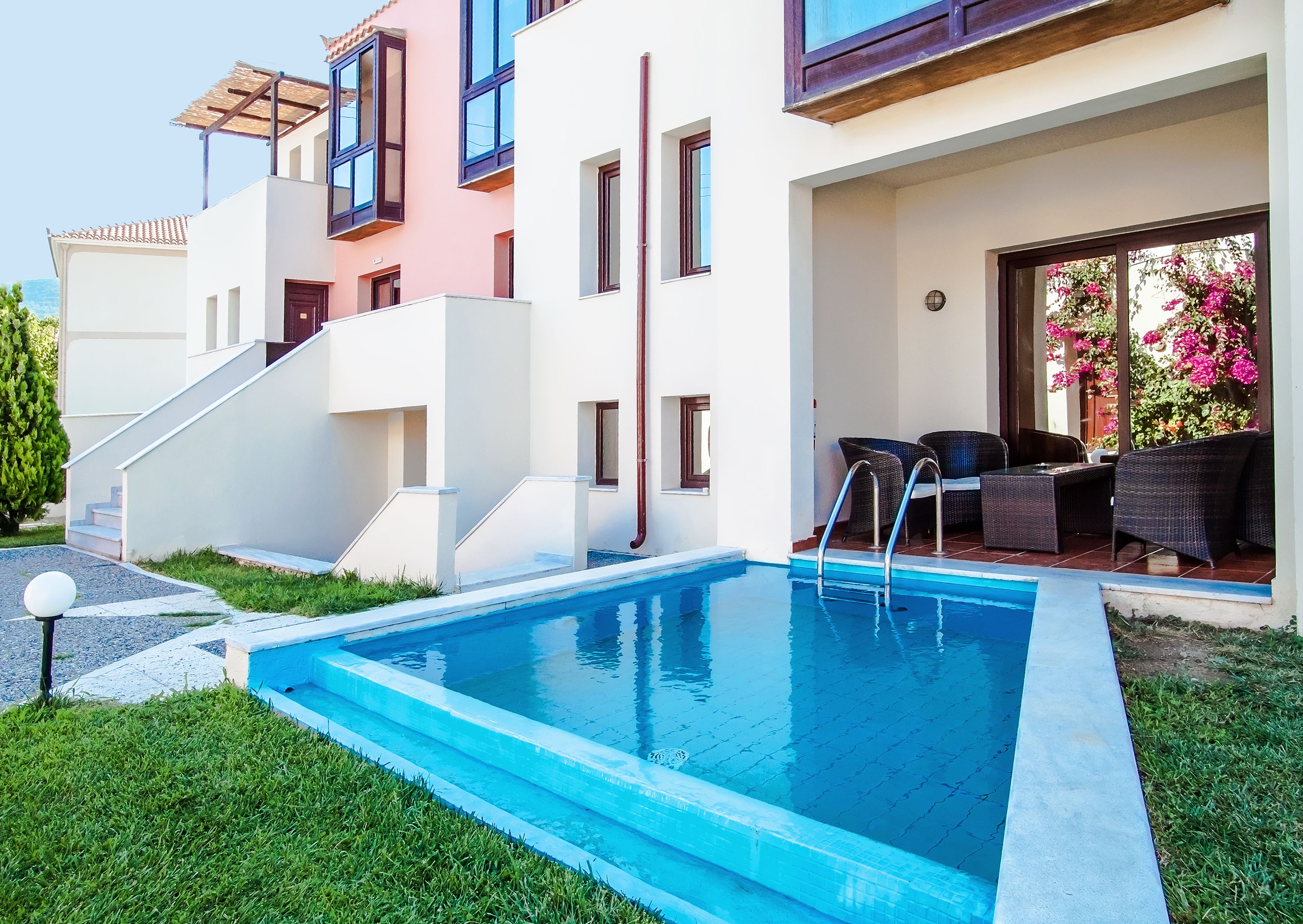 A modern building with a swimming pool, outdoor seating, and a staircase leading to the upper floors.