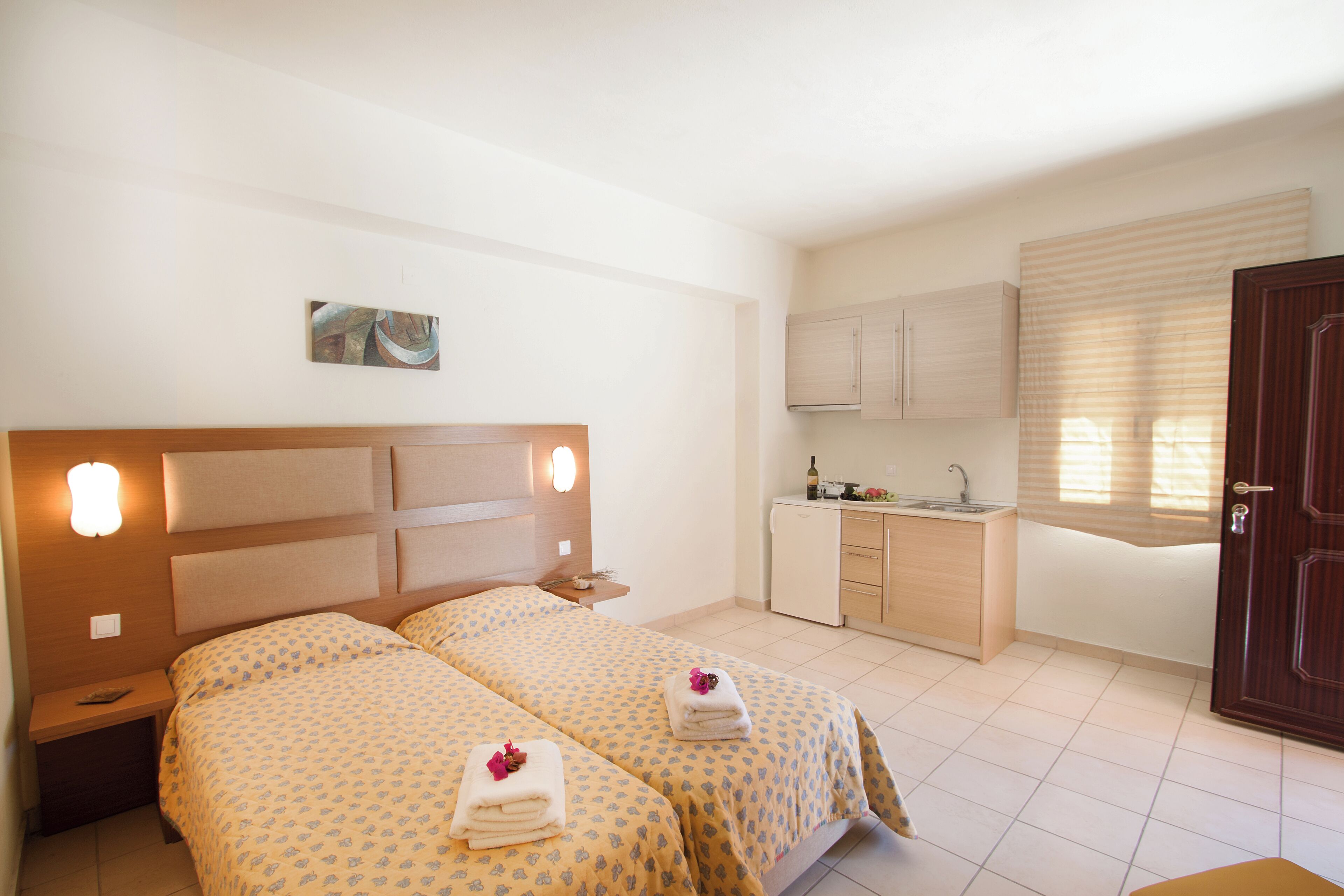 Ein Hotelzimmer mit zwei Betten, einer kleinen Küchenzeile und einem Badezimmer.