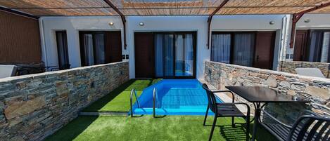 A pool area with stone walls, a small pool, and a table with chairs.