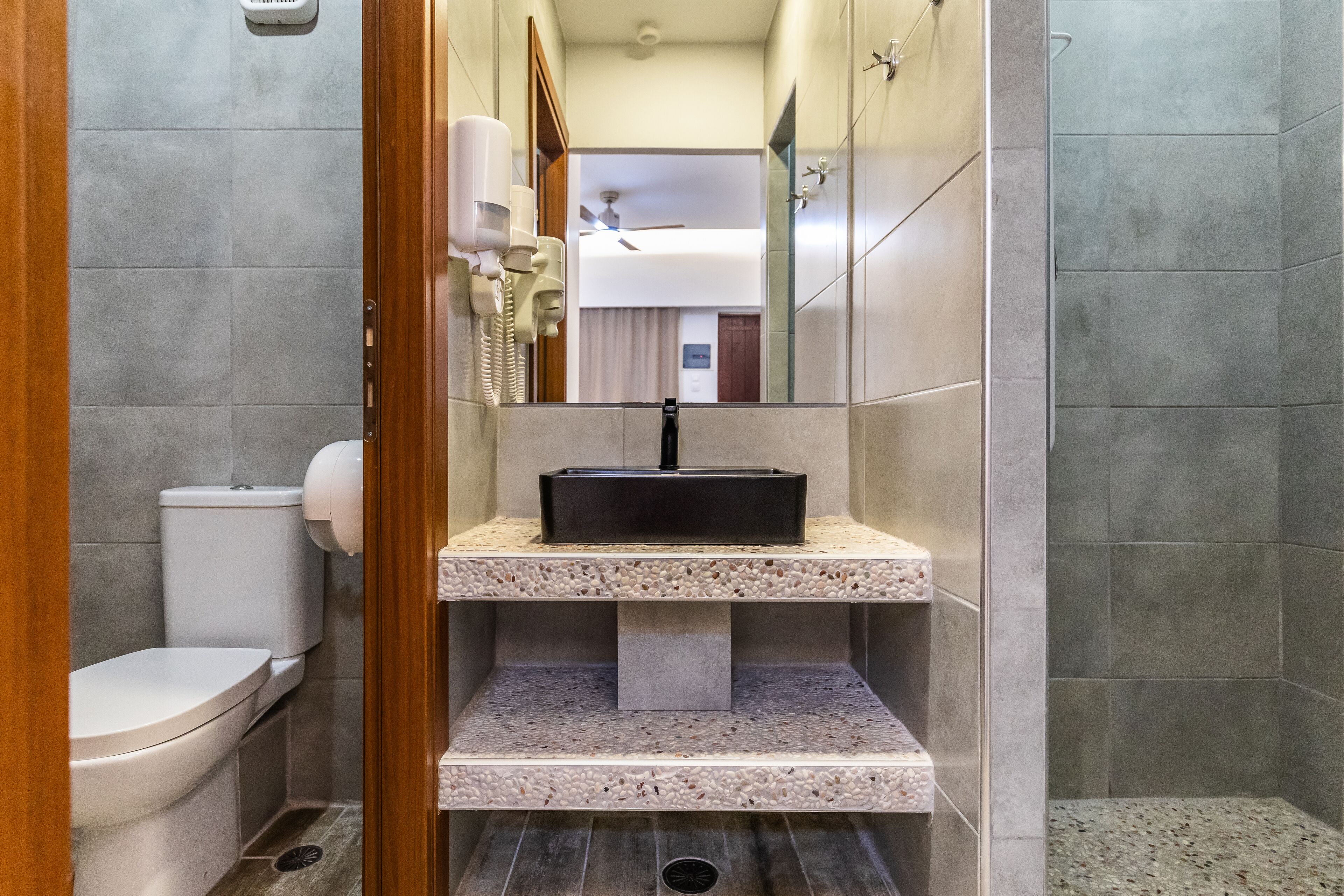 A modern bathroom with a toilet, a sink with a marble countertop, and a shower area.