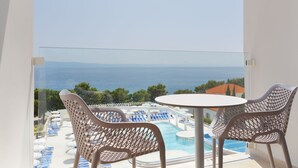 Un balcón con vistas a una piscina y al mar.