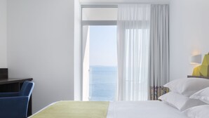 Una habitación de hotel con cama, escritorio y vista al mar.
