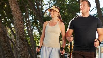 Two people walking outdoors, one holding a walking stick.