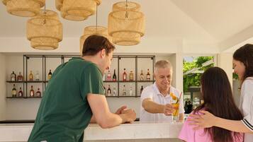 A bar area with a counter, shelves of liquor bottles, and wicker pendant lights.