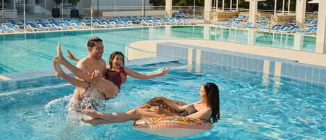 Una piscina con sillones de descanso y sombrillas.