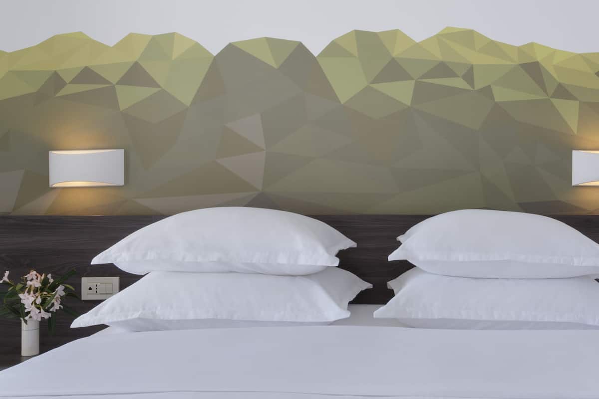 A bedroom with a geometric wall design, two bedside lamps, and a bed with multiple pillows.
