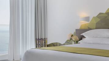 Una habitación de hotel con cama, mesita de noche, lámpara y vista al mar.