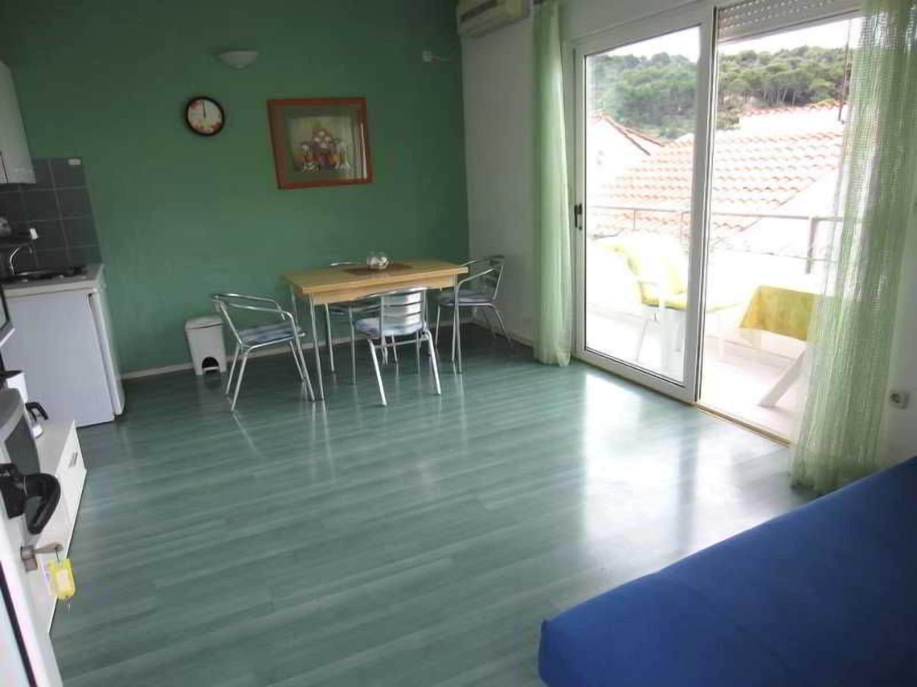 A room with a dining table and chairs, a kitchenette, and a sliding glass door to the outside.