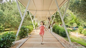 A covered walkway in a park with a person walking. - Bluesun Hotel Neptun (Tucepi)