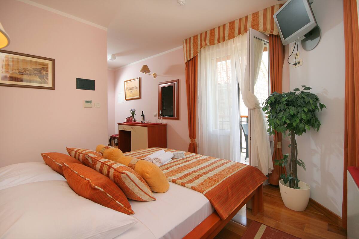 Una habitación de hotel con cama, escritorio, televisor y una planta en maceta.