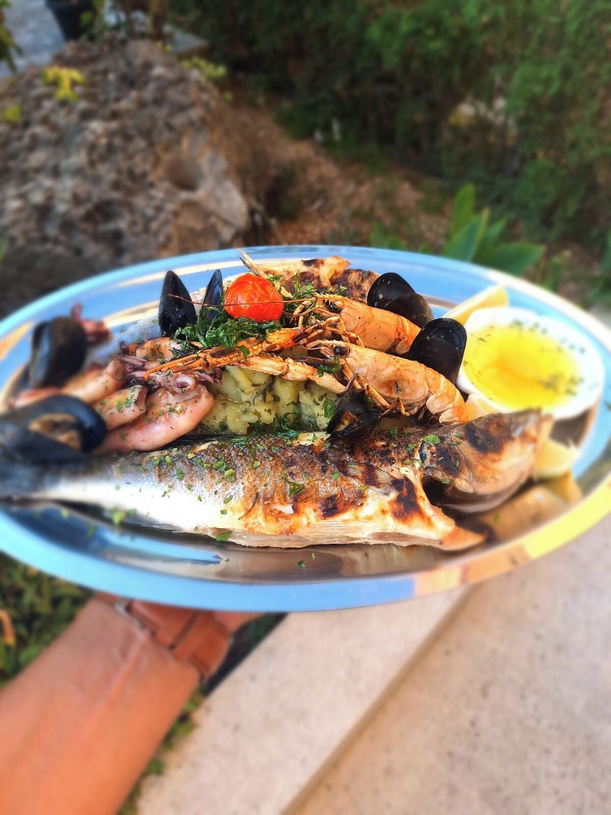 Un piatto di mare con pesce alla griglia, cozze e una fetta di limone.