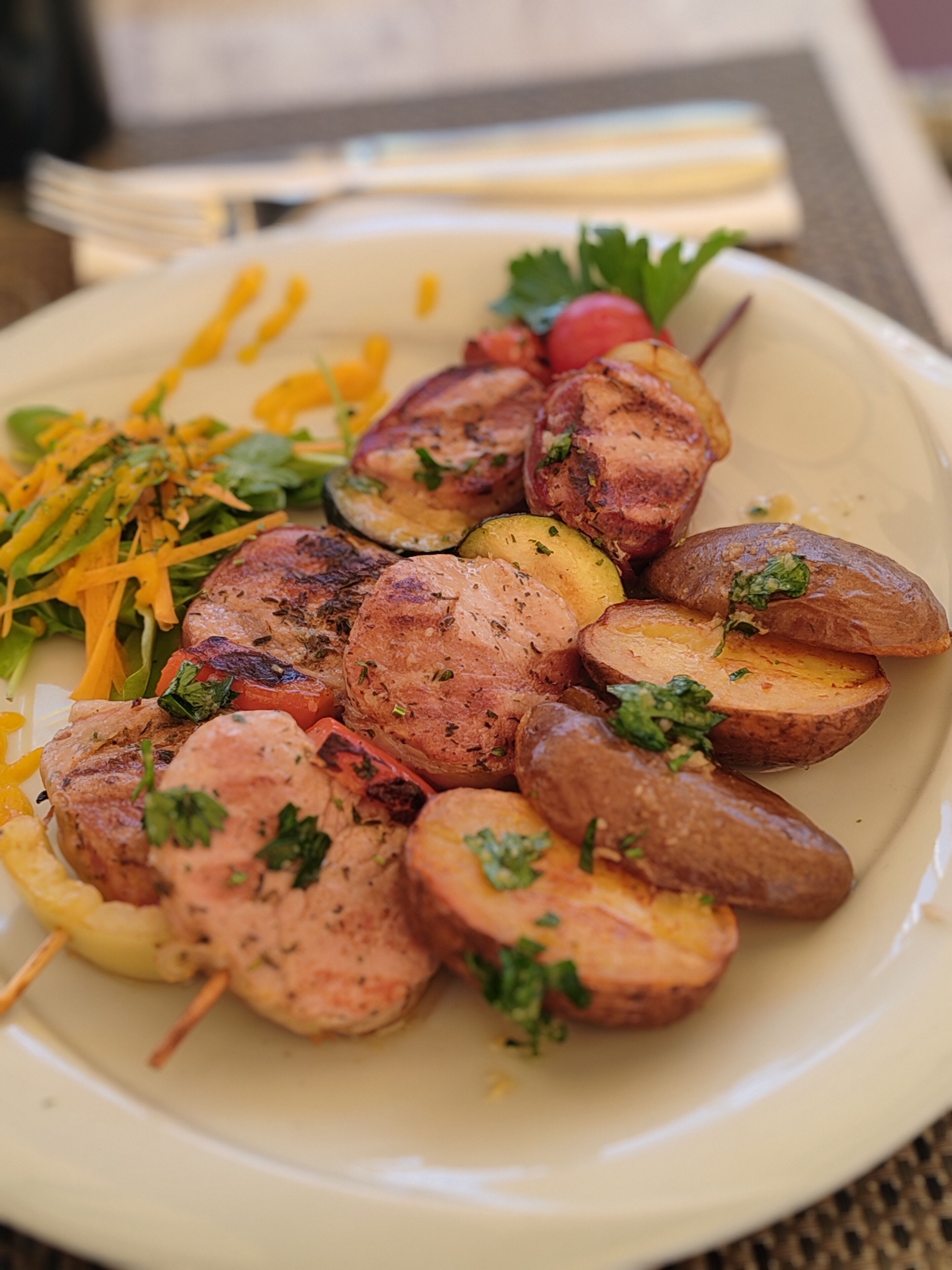 A plate of grilled chicken, roasted potatoes, and grilled vegetables.