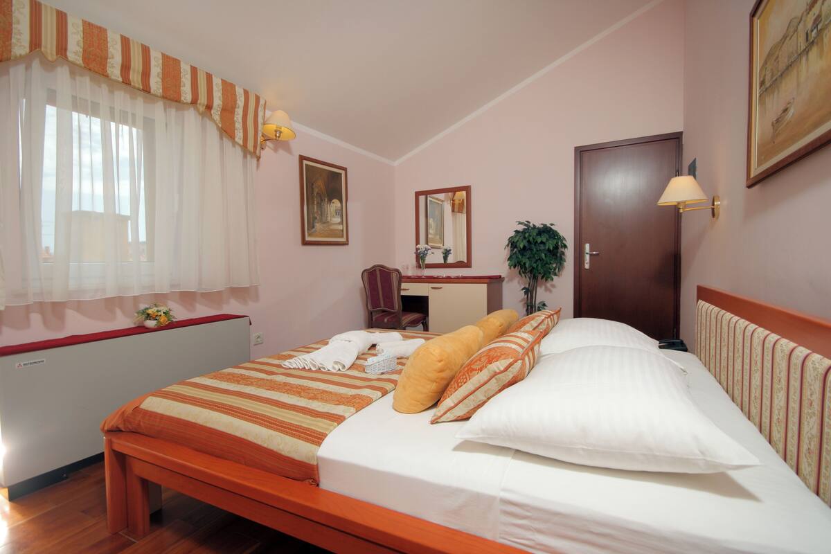 Un dormitorio con cama, escritorio, silla, espejo y puerta.