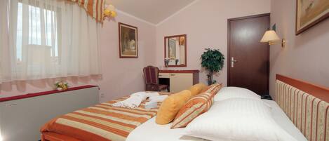 Un dormitorio con cama, escritorio, silla, espejo y puerta.