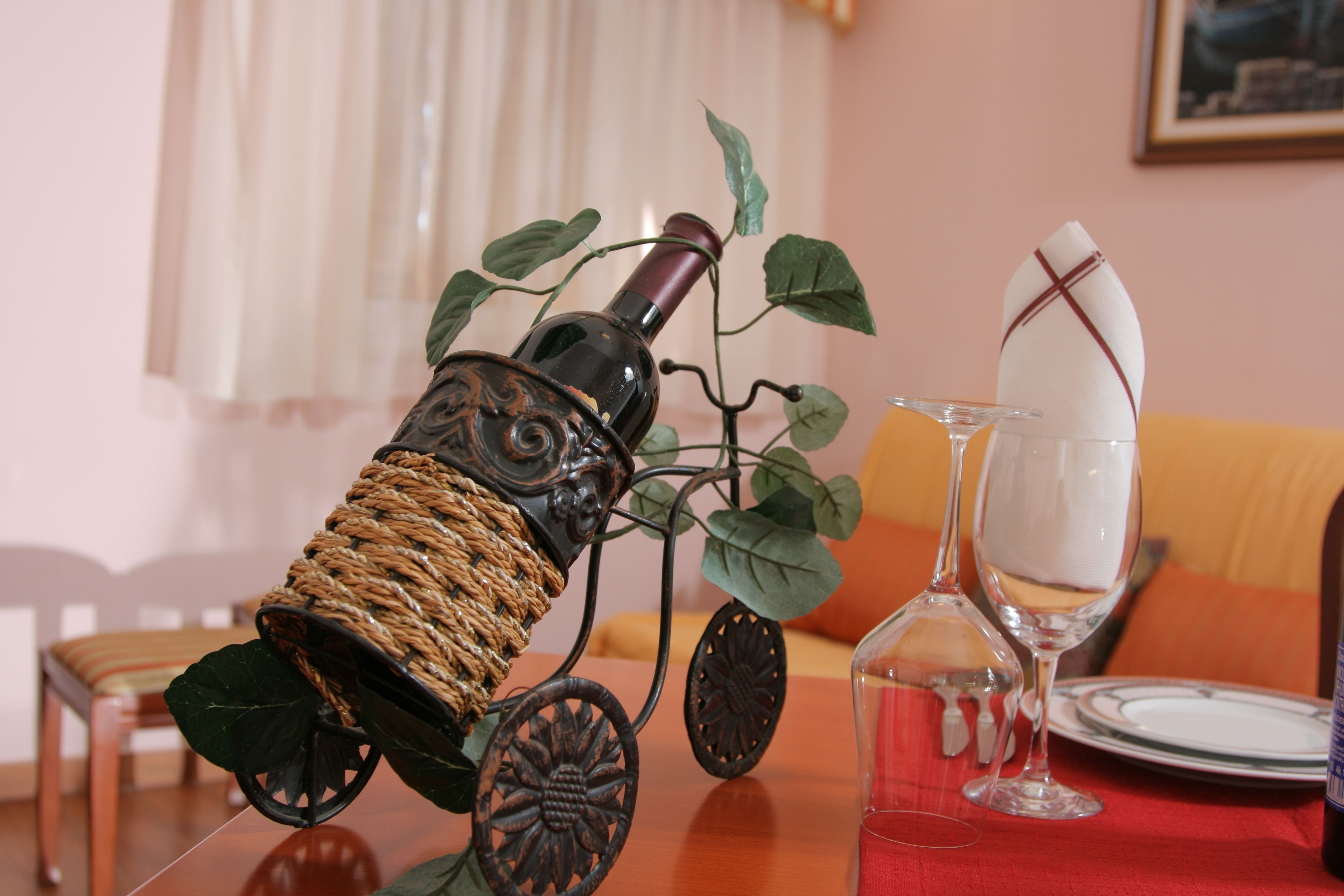 A dining table with a decorative bottle, a glass, and a woven basket.
