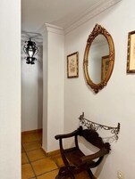A hallway with a wooden bench, a large ornate mirror, and a wall-mounted light fixture.