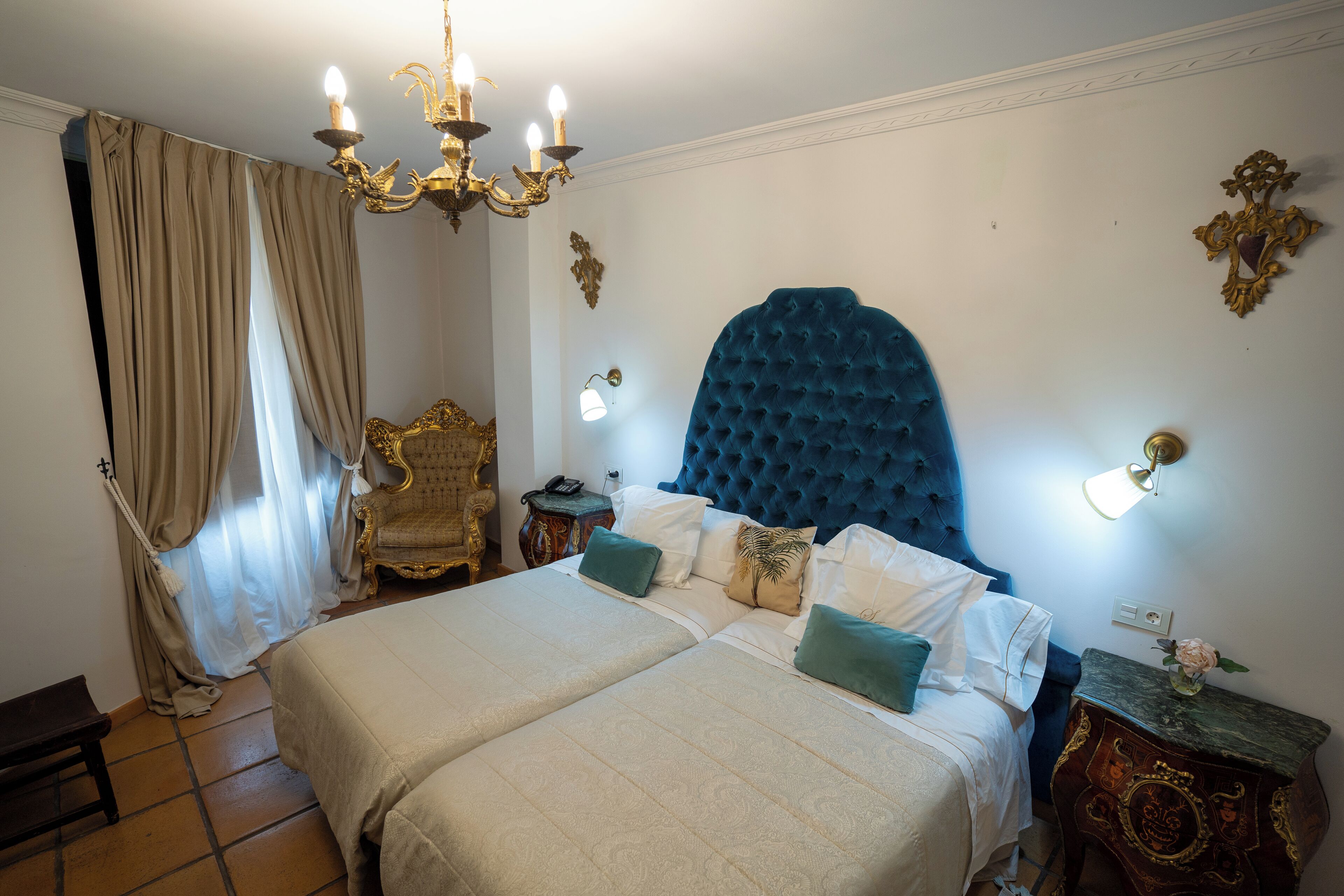 A bedroom with a large bed, two bedside tables, a chandelier, and a decorative wall piece.