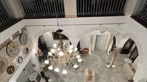 A spacious lobby with a high ceiling, a central chandelier, and a seating area with tables and chairs. - Hotel Convento La Gloria (Seville)