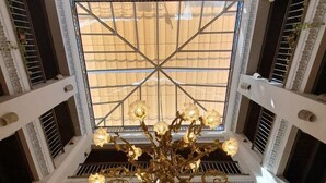 A multi-level atrium with a central chandelier, skylight, and arched staircases. - Hotel Convento La Gloria (Seville)