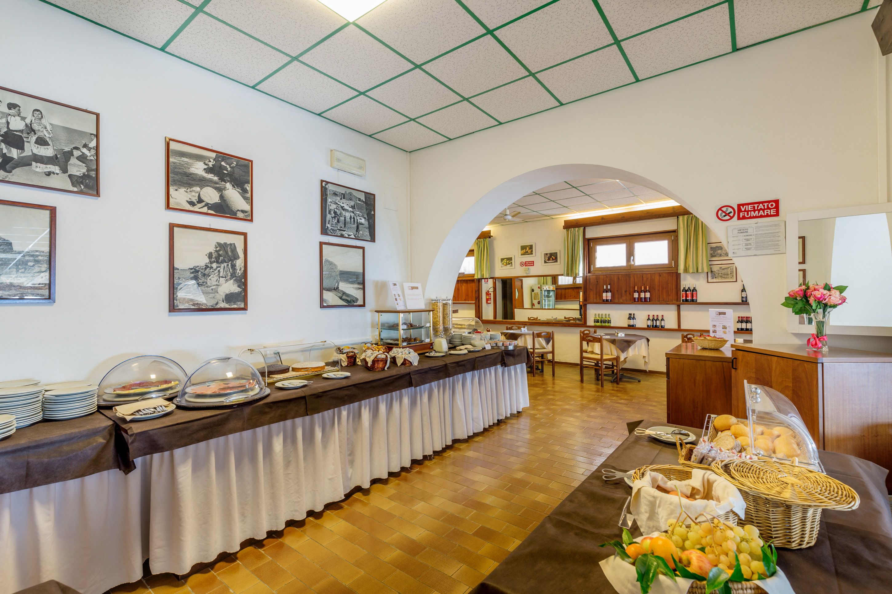 A buffet setup with a long table, various food items, and a wine display.