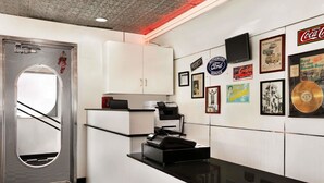 Une cuisine avec des armoires blanches, un plan de travail noir et un carrelage à motifs. Des photos encadrées et des objets de collection sont accrochés au mur.