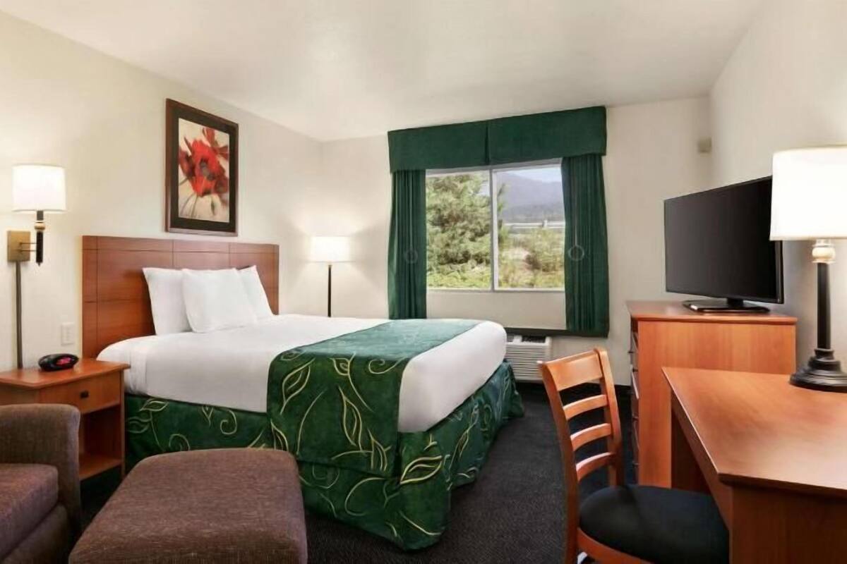 Een hotelkamer met een bed, bureau, televisie en zithoek.