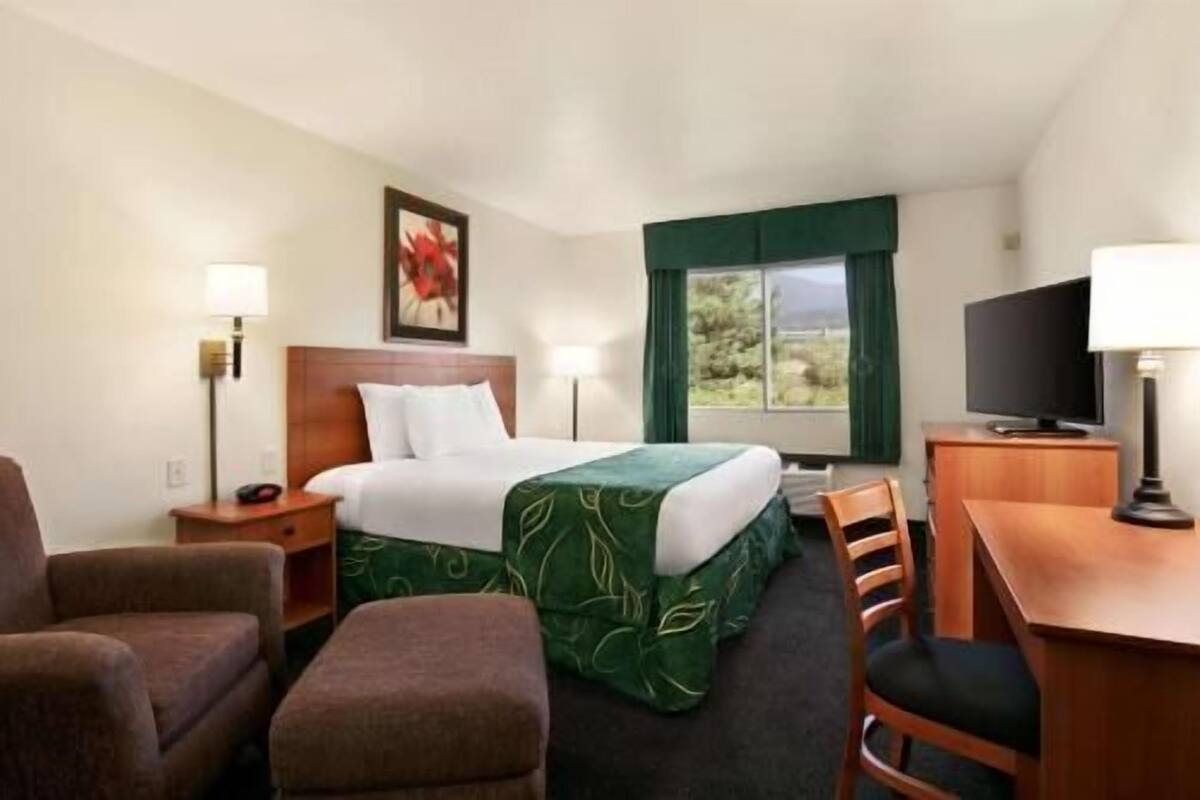 Een hotelkamer met een bed, een bureau, een stoel, een televisie en een raam met uitzicht.