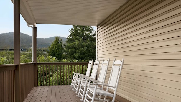 Une terrasse en bois avec des fauteuils à bascule et une vue sur une zone boisée.