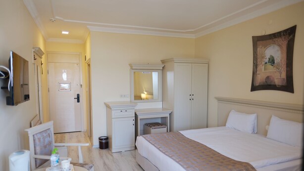 Une chambre d’hôtel avec un lit, un bureau doté d’un miroir, une armoire et un tableau au mur.