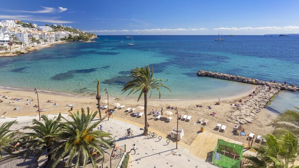 A beach with clear turquoise water, a sandy shore, and a few boats in the distance. - Hotel Ibiza Playa (Ibiza Town)