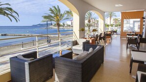 A seaside restaurant with outdoor seating, palm trees, and a view of the sea. - Hotel Ibiza Playa (Ibiza Town)