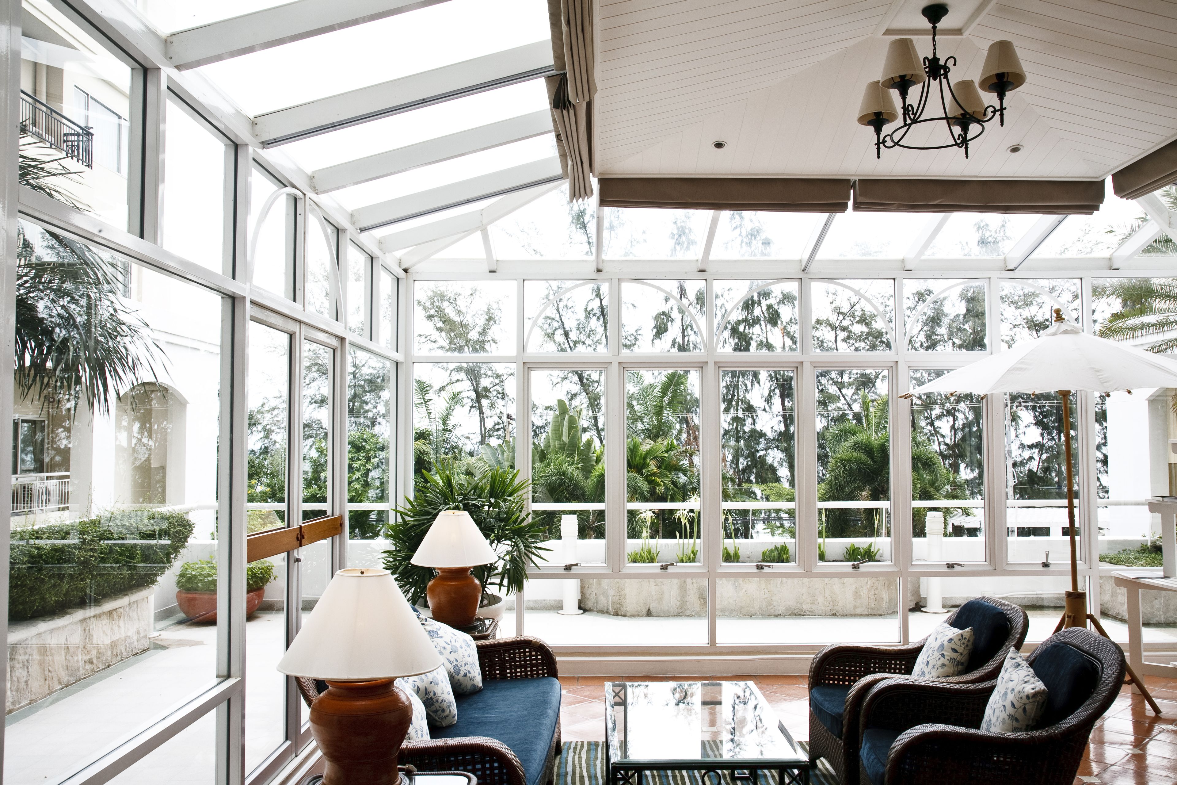 A spacious indoor area with large windows, wicker furniture, and a ceiling fan.