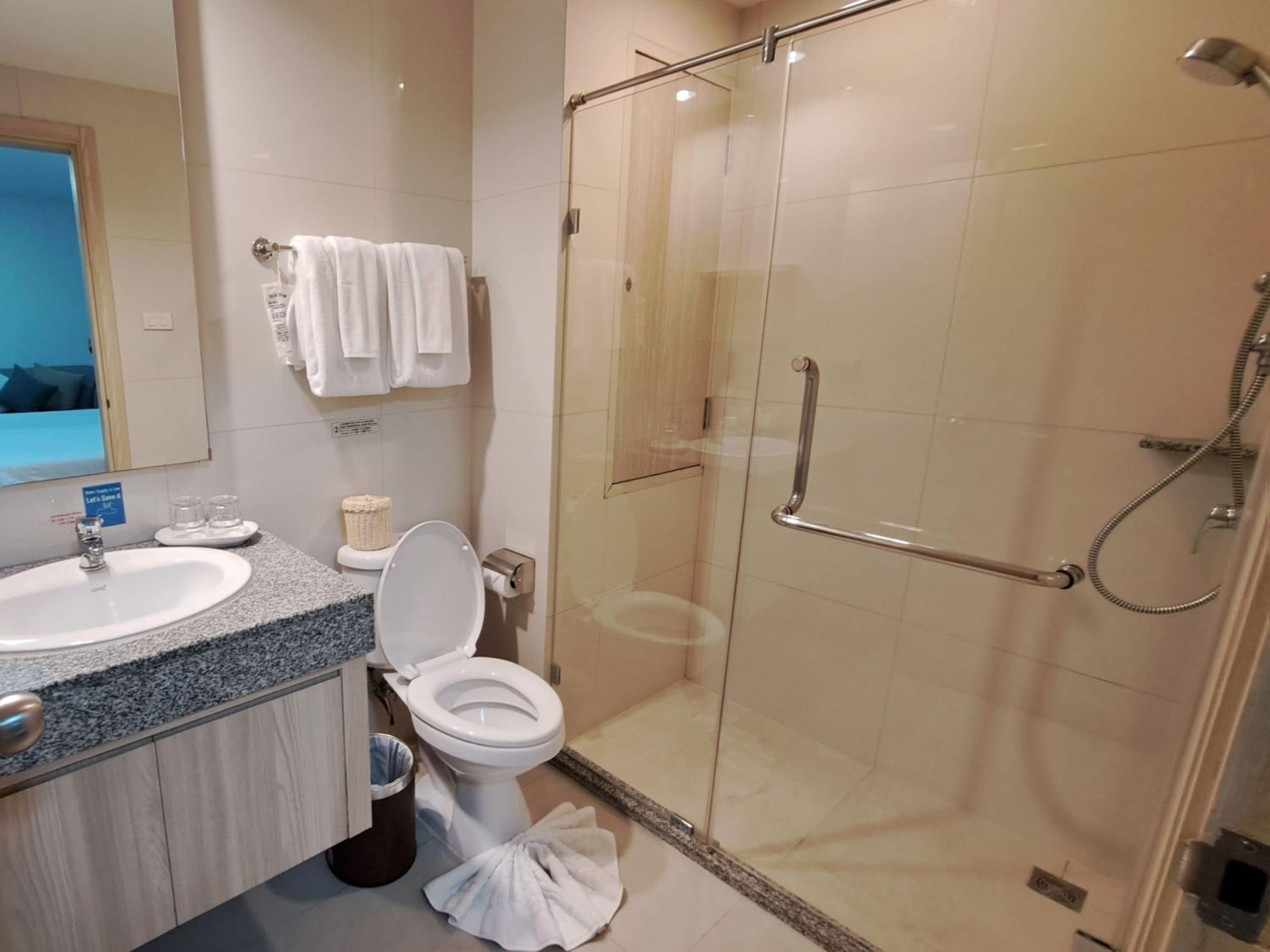 Une salle de bain moderne dotée d’une douche à parois de verre, d’un lavabo et de toilettes.